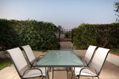 a table and chairs with a green table and a fence at SK-George Apartments by the Sea and Airport in Porto Rafti