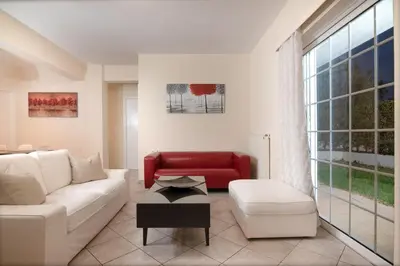 a living room with a white couch and a red chair at SK-George Apartments by the Sea and Airport in Porto Rafti