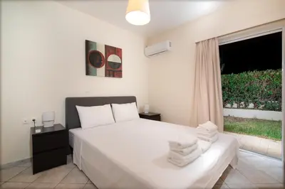 a bedroom with a white bed and a window at SK-George Apartments by the Sea and Airport in Porto Rafti
