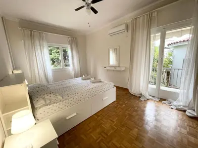 a bedroom with a large bed and two windows at Faliro Apartments Next To The Beach in Athens