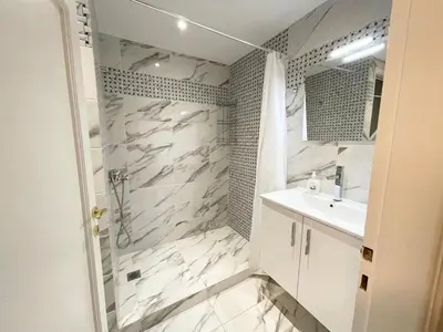 a white bathroom with a shower and a sink at Faliro Apartments Next To The Beach in Athens