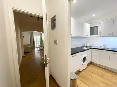 a kitchen with white cabinets and a washer and dryer at Faliro Apartments Next To The Beach in Athens