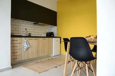 a kitchen with a black chair next to a counter at Deus Apartments_ Athens Airport in Spáta