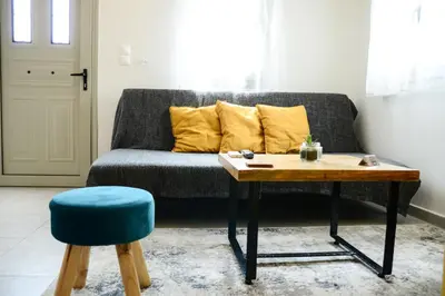 a living room with a couch with a table and a stool at Deus Apartments_ Athens Airport in Spáta