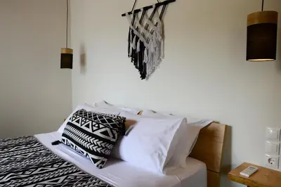 a bedroom with a bed with black and white pillows at Deus Apartments_ Athens Airport in Spáta