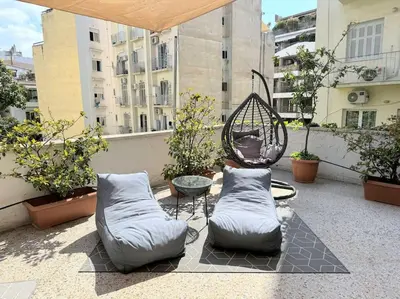 a patio with two pillows and a chair on a balcony at Amazing 3BDR Apt with Unique Roof Garden in Plaka in Athens