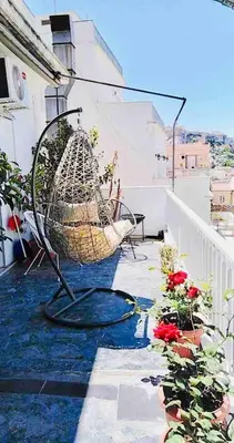 a basket chair sitting on a balcony with flowers at A Masterpiece in Plaka with Big Balcony and Acropolis View in Athens