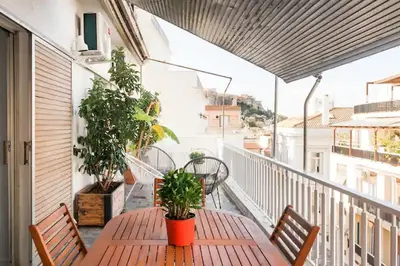 a wooden table on a balcony with plants on it at A Masterpiece in Plaka with Big Balcony and Acropolis View in Athens