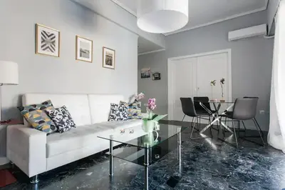 a living room with a white couch and a glass table at A Masterpiece in Plaka with Big Balcony and Acropolis View in Athens