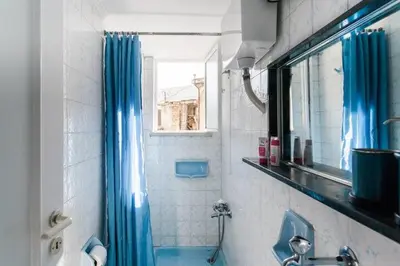 a bathroom with a shower with a blue shower curtain at A Masterpiece in Plaka with Big Balcony and Acropolis View in Athens