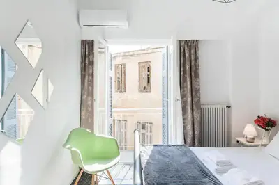 a white room with a green chair and a window at A Masterpiece in Plaka with Big Balcony and Acropolis View in Athens