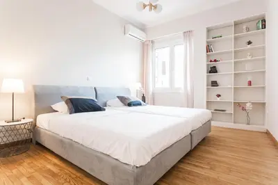 a white bedroom with a large bed with a blue headboard at HIGHEND 2BDR Full APT/ IDEAL LOCATION (and Netflix) in Athens