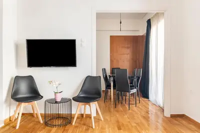 a dining room with black chairs and a flat screen tv at 2BDR Boutique Full Apt in Plaka (BIG BALCONY) in Athens