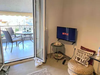 a living room with a tv and a table with chairs at OpenAir HOT TUB/Big Balcony/Great Boutique Apt in Athens