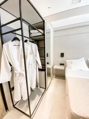 a bedroom with a white suit on a rack at Royalty Hotel Athens in Athens