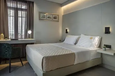 a bedroom with a bed and a desk and a window at Royalty Hotel Athens in Athens