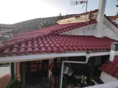 a man standing in front of a building with a red roof at WHOLE HOUSE NEAR THE BEACH WITH AMAZING VIEW in Kalívia Thorikoú