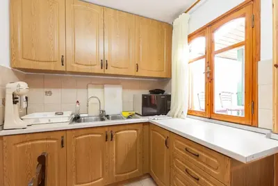 a kitchen with wooden cabinets and a sink and a window at WHOLE HOUSE NEAR THE BEACH WITH AMAZING VIEW in Kalívia Thorikoú