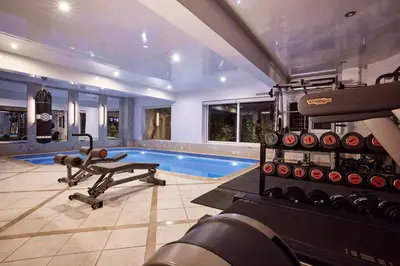 a fitness room with a gym with a swimming pool at Grystal Green Properites in Athens