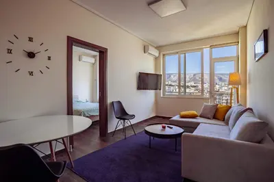 a living room with a couch and a table and a clock at Acropolis Comfy Home in the Heart of Athens for 4 by Filos Inc in Athens