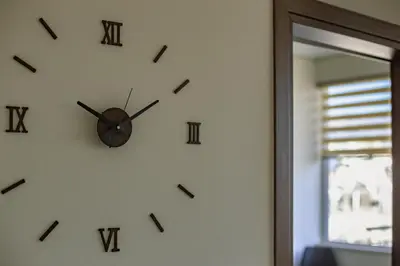 a clock on a wall with roman numerals at Acropolis Comfy Home in the Heart of Athens for 4 by Filos Inc in Athens