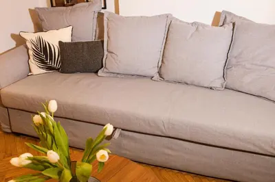 a grey couch with pillows and a vase with flowers at Central Comfy Modern Flat 2 bedrooms 2 bathrooms in Athens