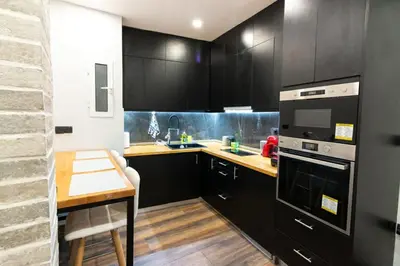 a kitchen with black cabinets and a wooden table at Double Romantic Suite in Athens