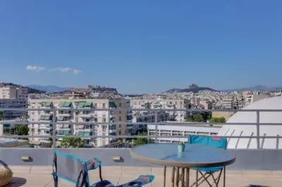 a table and chairs on a balcony with a city at Studio with private terrace and view of Acropolis! in Athens