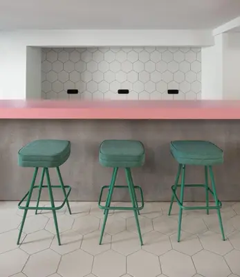 two green bar stools in front of a pink counter at COLORS Hotel Athens in Athens