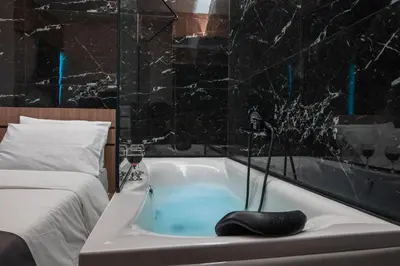 a bathroom with a bath tub next to a bed at NOHO Boutique , premium living Lazeon 7 in Athens