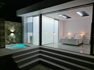 a master bedroom with a tub and a bed at Olivujoj Villajoj - Deluxe Villa with Detached Pool House in Anavissos