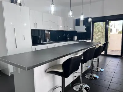 a kitchen with a black counter and black chairs at Olivujoj Villajoj - Deluxe Villa with Detached Pool House in Anavissos