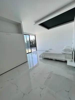 a white bedroom with a bed and a large marble floor at Olivujoj Villajoj - Deluxe Villa with Detached Pool House in Anavissos