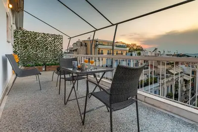 a balcony with a table and chairs on a roof at Athens Acropolis House in Athens