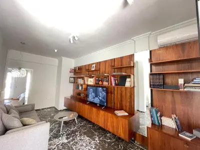 a living room with wooden book shelves and a couch at Plato - Acropolis Residence Apartment in Athens