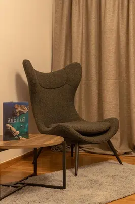a chair in a living room next to a table at Plato - Acropolis Residence Apartment in Athens
