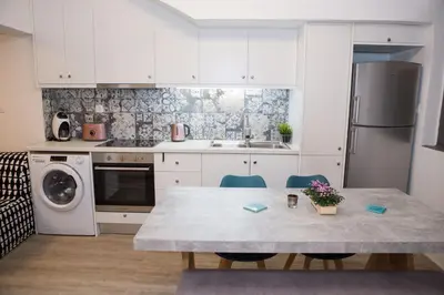 a kitchen with white cabinets and a table with chairs at Stylish, comfortable, basement loft-like apartment with amenities in Athens