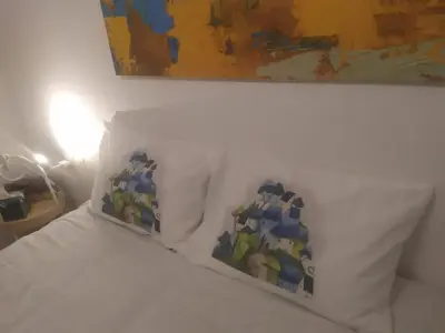 a white bed with two pillows sitting under a painting at Stylish, comfortable, basement loft-like apartment with amenities in Athens