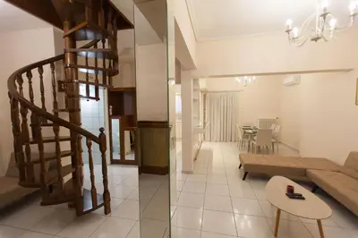 a living room and dining room with a spiral staircase at Acropolis view and 360 degrees in Athens