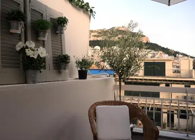 a wicker chair sitting on a balcony with plants at Top of the city Central studio with Acropolis View in Athens