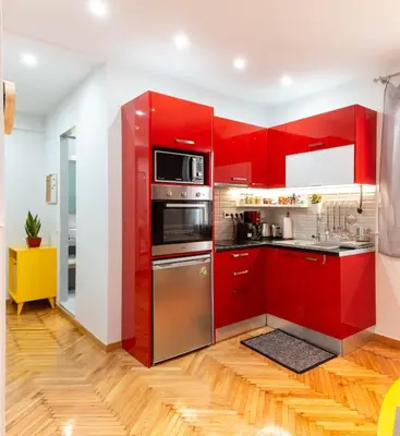 a red kitchen with stainless steel appliances and red cabinets at Martin's Akropolis Studio in Athens