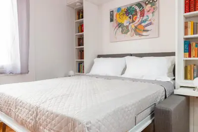 a white bedroom with a large bed with bookshelves at Martin's Akropolis Studio in Athens