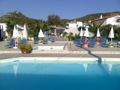 a large swimming pool with chairs and umbrellas at Helios Hotel in Agia Marina Aegina