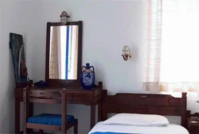 a bedroom with a bed and a mirror and a dresser at Helios Hotel in Agia Marina Aegina