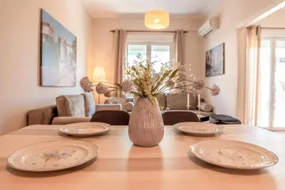 a dining room table with plates and a vase with flowers at Acropolis museum grand apartment in Athens