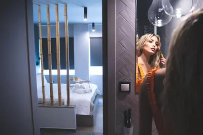 a woman brushing her teeth in front of a mirror at Rooster Suites in Athens
