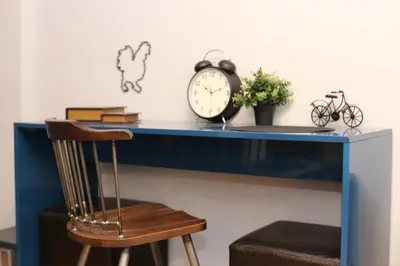 a blue desk with a clock and a chair at Rooster Suites in Athens