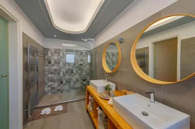 a bathroom with a sink and a shower and mirrors at The Painters Luxurious villa in Anavissos
