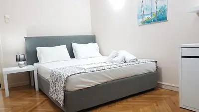a bed with white sheets and pillows in a room at Olive Apartment- Athens Center, 4 BD, 1.5 BATH in Athens