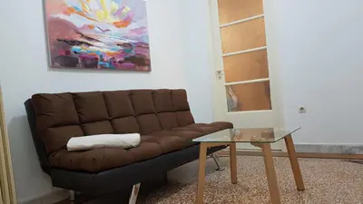 a brown couch sitting in a living room with a table at Olive Apartment- Athens Center, 4 BD, 1.5 BATH in Athens